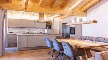 A modern kitchen with wooden beams, a dining area with a wooden table and chairs, and a built-in bench.