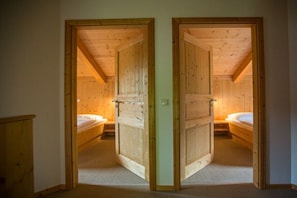 A room with two wooden doors leading to a bedroom with a single bed. - Cabin in Annaberg with swimming pool (Annaberg)