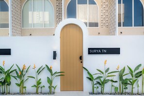 A building with a wooden door, a sign reading 'SURYA TN', and a row of plants in front. - Surya TN Villa by Betterplace (Pecatu)
