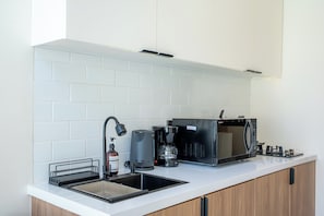 A modern kitchen with a built-in dishwasher, a coffee machine, and a microwave. - Surya TN Villa by Betterplace (Pecatu)