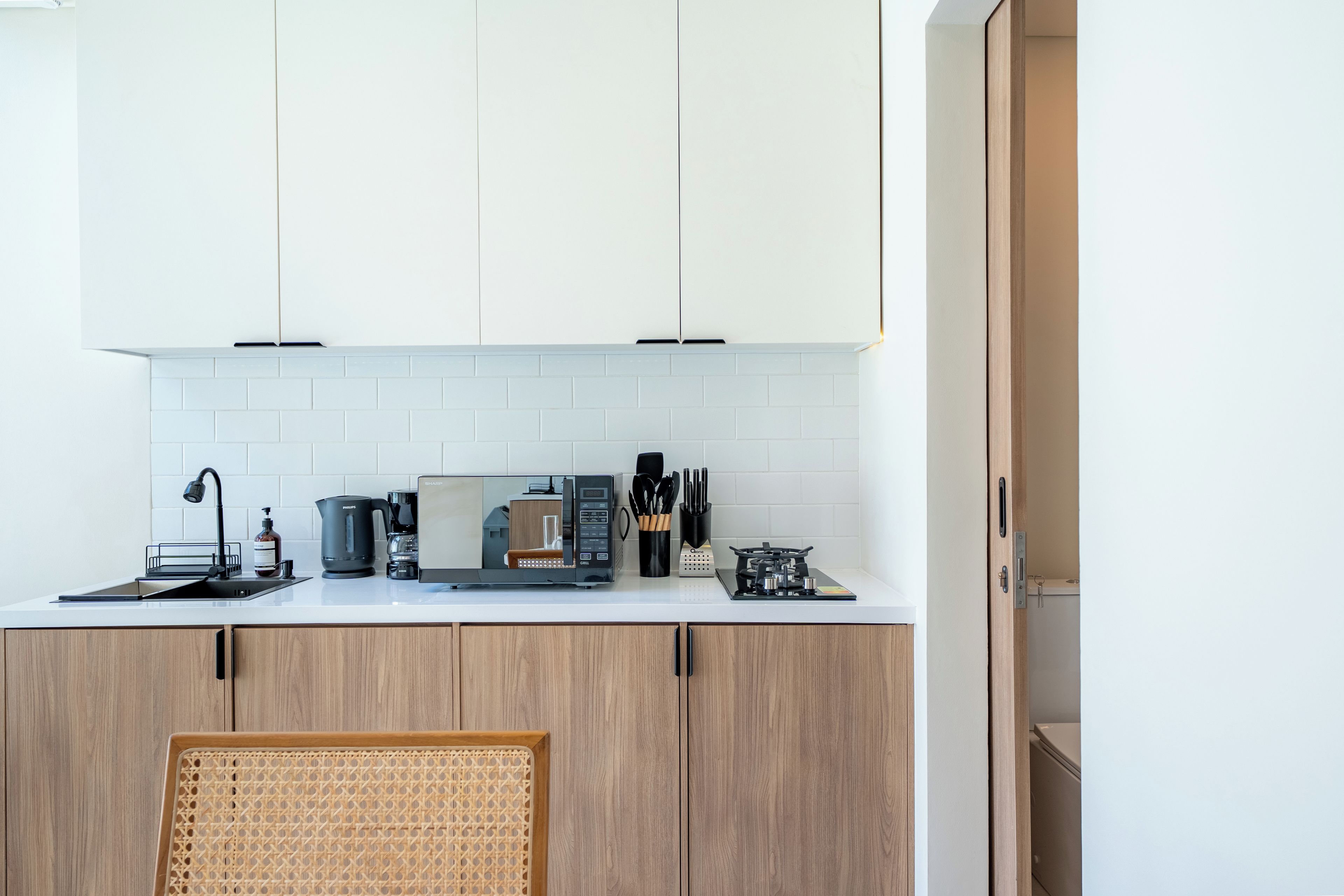 Cozinha moderna com armários brancos, cafeteira, chaleira e fogão.