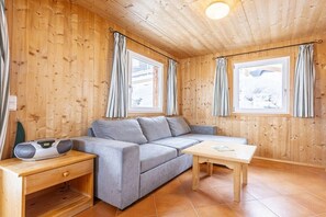 Ein gemütliches Zimmer mit einer Couch, einem Tisch und Vorhängen.
