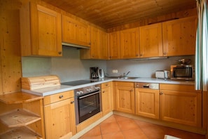 A kitchen with wooden cabinets, a built-in oven, a microwave, and a toaster. - Cabin in Annaberg with swimming pool (Annaberg)