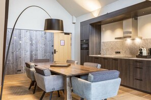 Een moderne keuken met donker houten kastjes, een inbouwoven en een grote eettafel met comfortabele stoelen.