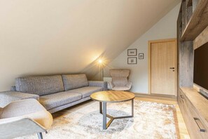 A modern living room with a sectional sofa, a round coffee table, and a chair. - Superior penthouse with 2 bedrooms (Schruns)