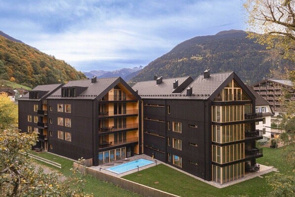 A multi-story building with balconies, a swimming pool, and a mountainous backdrop. - Apartment in Schruns with swimming pool (Schruns)