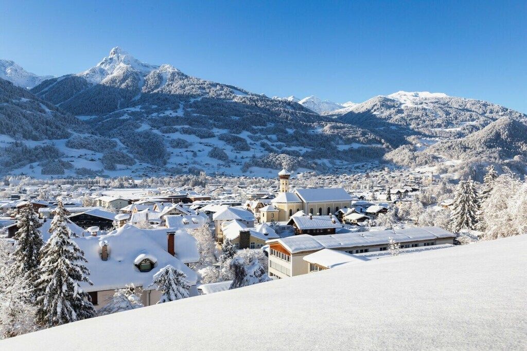 A snow-covered town with buildings and a mountain in the background.