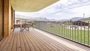 Eine Holzterrasse mit Blick auf Berge und einem eingezäunten Bereich.