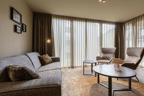 A modern living room with a sofa, armchairs, a coffee table, and a large window with curtains. - Apartment in Schruns with swimming pool (Schruns)