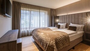 Une chambre d’hôtel moderne dotée d’un grand lit, d’un téléviseur à écran plat et d’une grande fenêtre avec des rideaux.