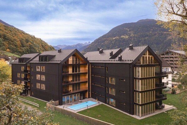 A multi-story building with balconies, a swimming pool, and a mountainous backdrop. - Apartment in Schruns with swimming pool (Schruns)