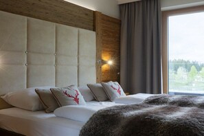 Ein Schlafzimmer mit einem großen Bett, einem Holzkopfstück und einem Fenster mit Blick.