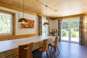 Un espace repas avec une longue table, des chaises en bois et des luminaires suspendus.