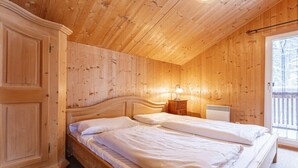 Una habitación con paneles de madera, una cama, una mesita de noche y una ventana.