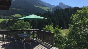 Una terraza con mesa y sillas, con vista a un paisaje montañoso.