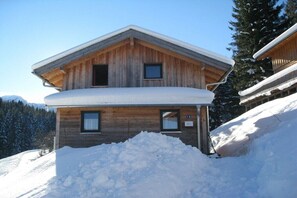 A wooden chalet with a sloped roof and a snow-covered balcony. - Cabin in Annaberg with swimming pool (Annaberg)
