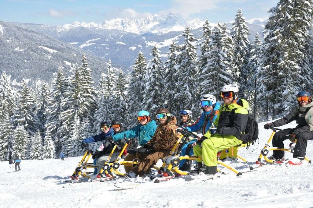 Un gruppo di persone su un motoslitta in una zona montana innevata.