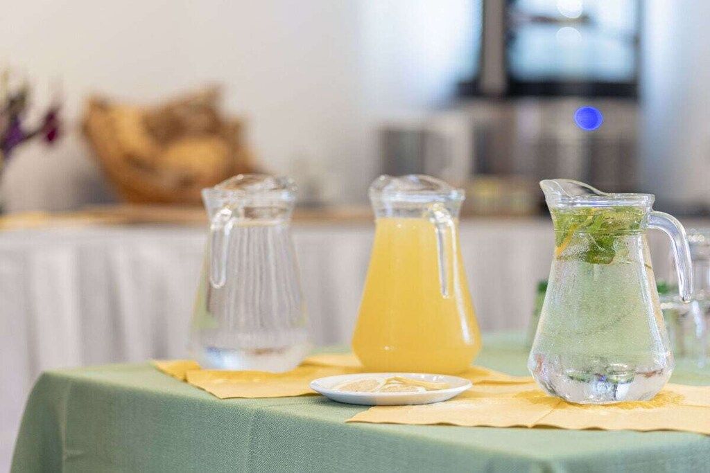 A table with two pitchers and a glass jug, possibly containing beverages, on a tablecloth.