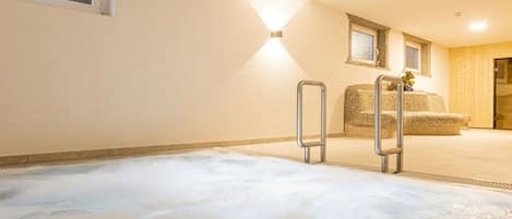 Un área de spa con un jacuzzi, un banco de madera y una lámpara fijada a la pared.