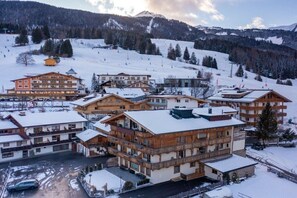 Estância de montanha coberta de neve, com edifícios de vários andares, pistas de esqui e céu limpo.