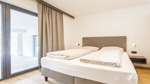 Ein modernes Schlafzimmer mit einem großen Bett, einer Schiebetür zum Balkon und einer neutralen Farbgestaltung.