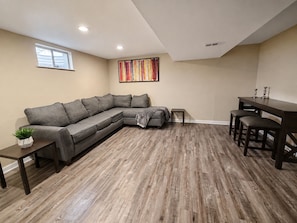 A living room with a sectional sofa, a small table, and a dining area with a table and chairs. - Spacious 5BR Denver Home Near Downtown & Hospitals (Denver)