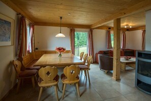 A wooden dining area with a table and chairs, a sofa, and a television. - Cabin in Annaberg with swimming pool (Annaberg)