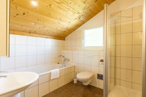 A bathroom with a wooden ceiling, a bathtub, a toilet, and a shower. - Cabin in Annaberg with swimming pool (Annaberg)