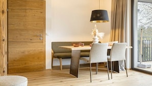 Uma sala de jantar com mesa, cadeiras, luminária e um banco.