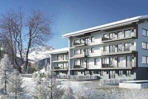 Ein mehrstöckiges Gebäude mit Balkonen, umgeben von schneebedeckten Bäumen und Bergen.