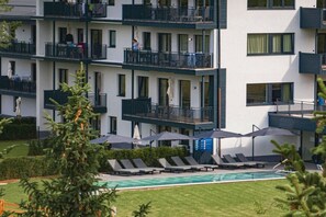 Un hotel a più piani con balconi, una piscina e area salotto all'aperto.