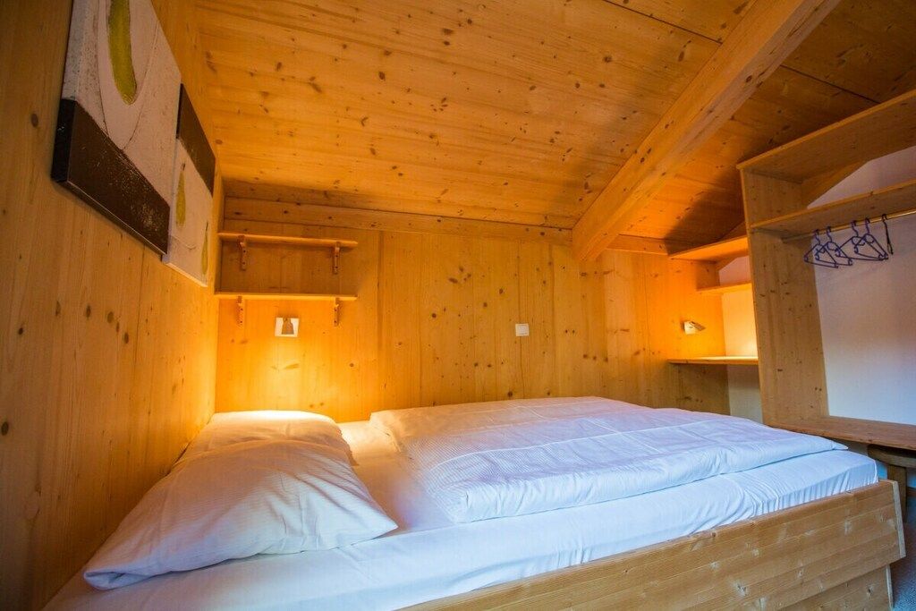 Une pièce de cabane en bois avec un lit, des murs en bois et un plafond en pente.