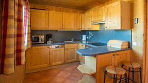 Una cocina con gabinetes de madera, microondas, cafetera y pileta.