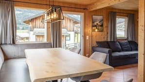 Un interior de madera con una mesa de comedor, sofá y vistas al exterior.