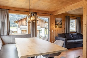 Een houten interieur met een eettafel, bank en uitzicht op buiten.