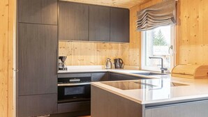 Una cocina moderna con armarios oscuros, un lavamanos de acero inoxidable y una ventana con vistas.