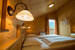 A wooden room with two beds, a window with curtains, and a wall-mounted lamp. - Cabin in Annaberg with swimming pool (Annaberg)