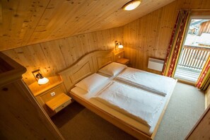 Ein Schlafzimmer einer Holzhütte mit einem Bett, Nachttischlampen und einem Fenster mit Vorhängen.
