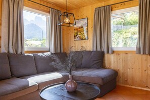 A modern living room with a sectional sofa, a round coffee table, and a hanging light fixture. - Cabin in Annaberg with swimming pool (Annaberg)