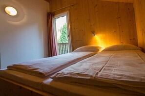 A single bed with a headboard, a bedside lamp, and a window with a view of trees. - Cabin in Annaberg with swimming pool (Annaberg)