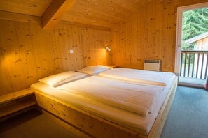 A wooden room with a double bed, a bench, and a view of the outdoors. - Cabin in Annaberg with swimming pool (Annaberg)