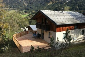 A two-story wooden cabin with a balcony, a deck, and a view of a forested valley. - Cabin in Annaberg with swimming pool (Annaberg)