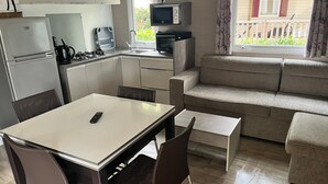 Een knus woongedeelte met kitchenette, een eethoek en een bank.