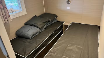 Ein kleines Zimmer mit einem Bett, einem Fenster mit Vorhängen und einer Tür.
