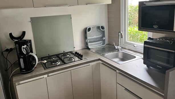 Een moderne keuken met een Bosch koffiezetapparaat, een magnetron en een spoelbak.