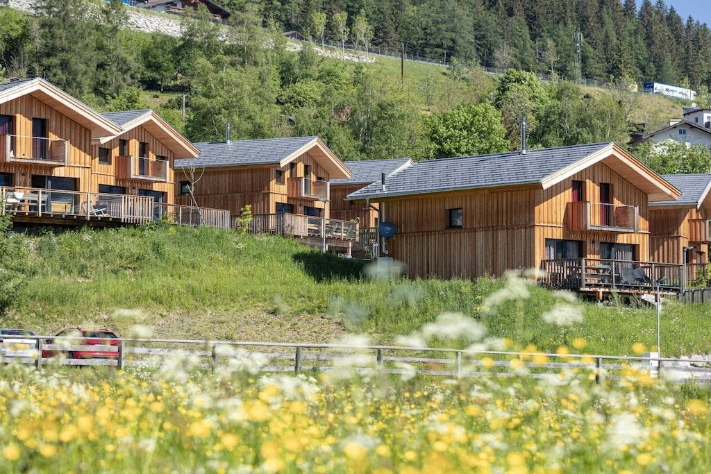 Eine Reihe von Holzhütten mit Balkonen, vor einer Hügellandschaft gelegen.