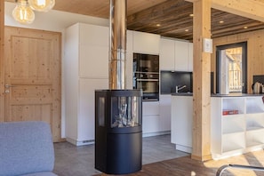 Een moderne keuken met witte kastjes, een roestvrijstalen afzuigkap en een houtkachel.