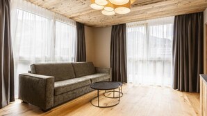 Een moderne woonkamer met een bank, een rond bijzettafeltje en een houten plafond.