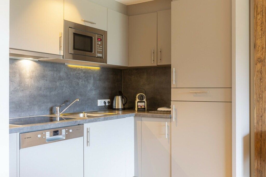 Een moderne keuken met een Bosch vaatwasser, een magnetron en een waterkoker op het aanrecht.