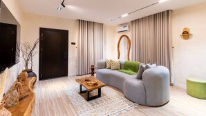 Een moderne woonkamer met een grijze bank, een houten bijzettafeltje en een kamerbreed tapijt met een patroon.